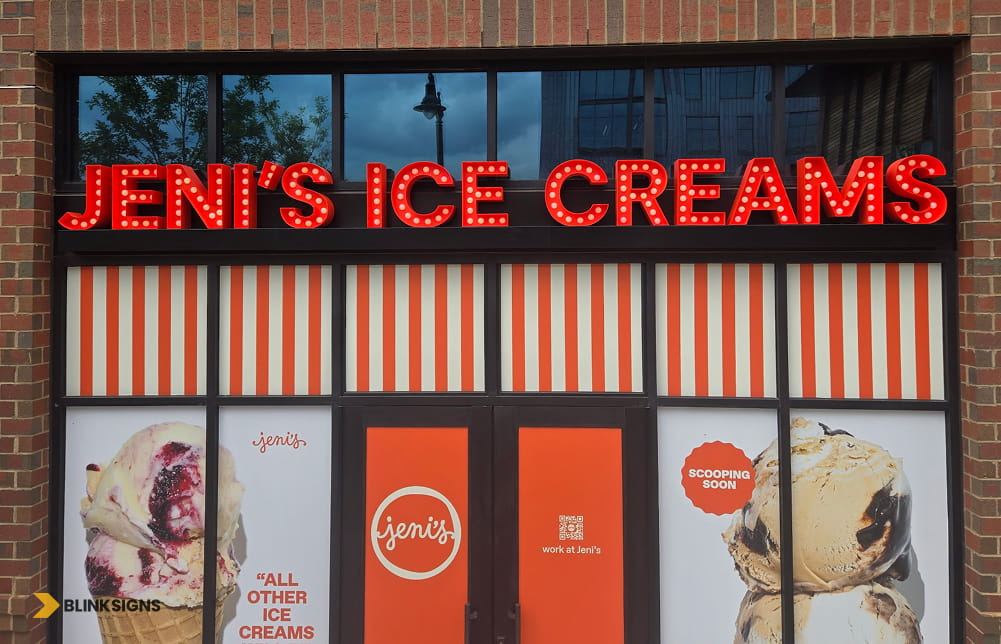 Brightly illuminated Jeni's Ice Creams marquee channel letter storefront sign installed on a brick building.