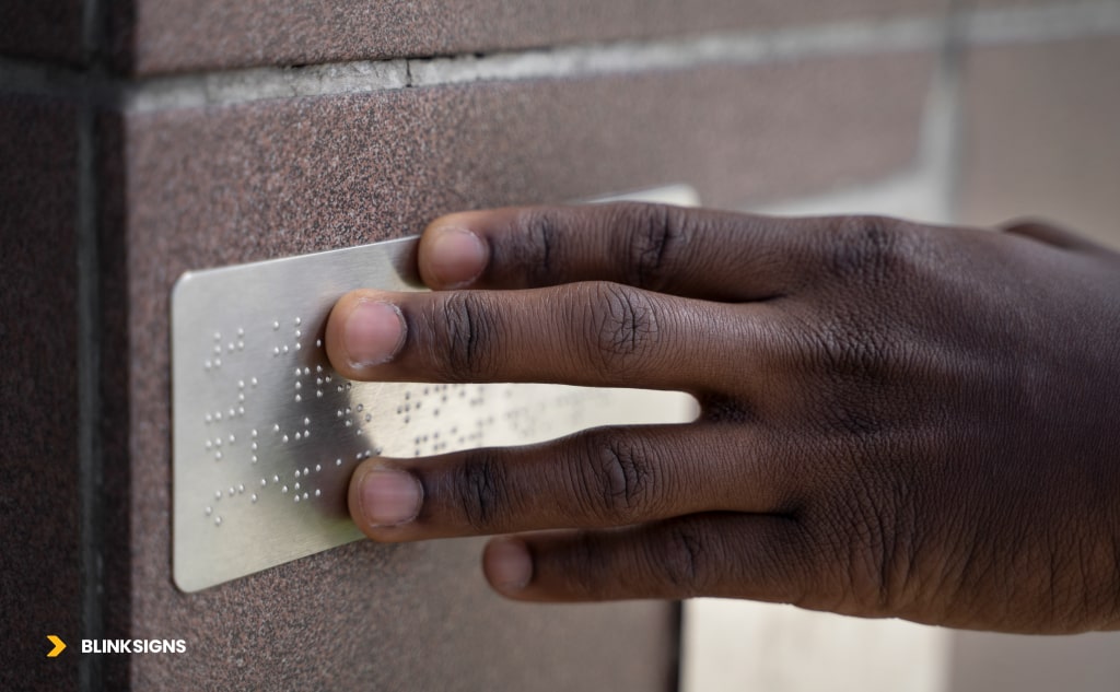 hand touching Tactile letters on a sign