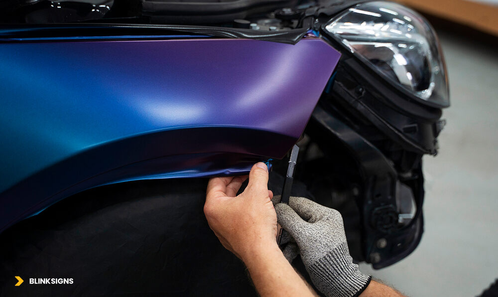 hands of worker setting edges during vehicle wrap after disassembling car front bumper