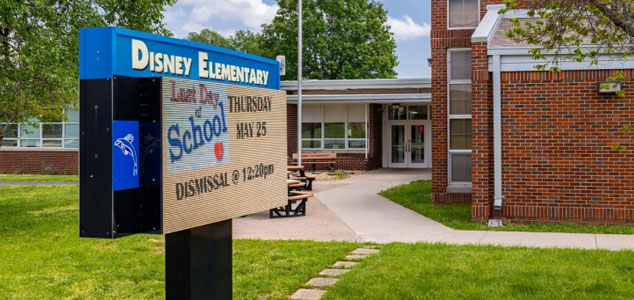 a pole sign for school Disney Elementary on a green area of school